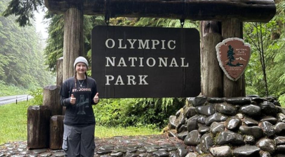 Ashlee standing in front of the sign for Olympic National Park.